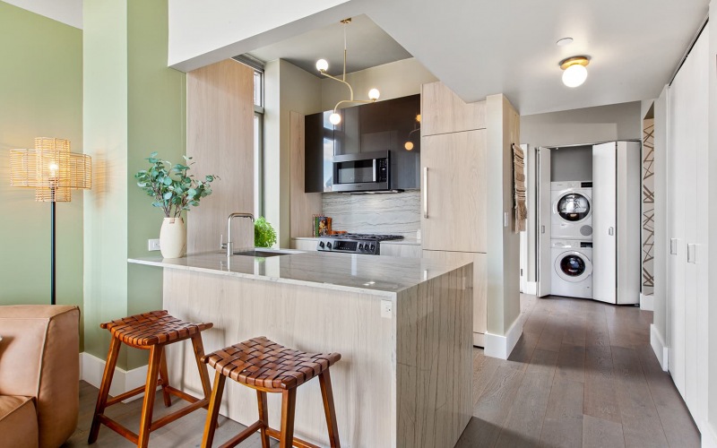 a kitchen area that's connected to the living room and a hallway leading to a stacked washer and dryer